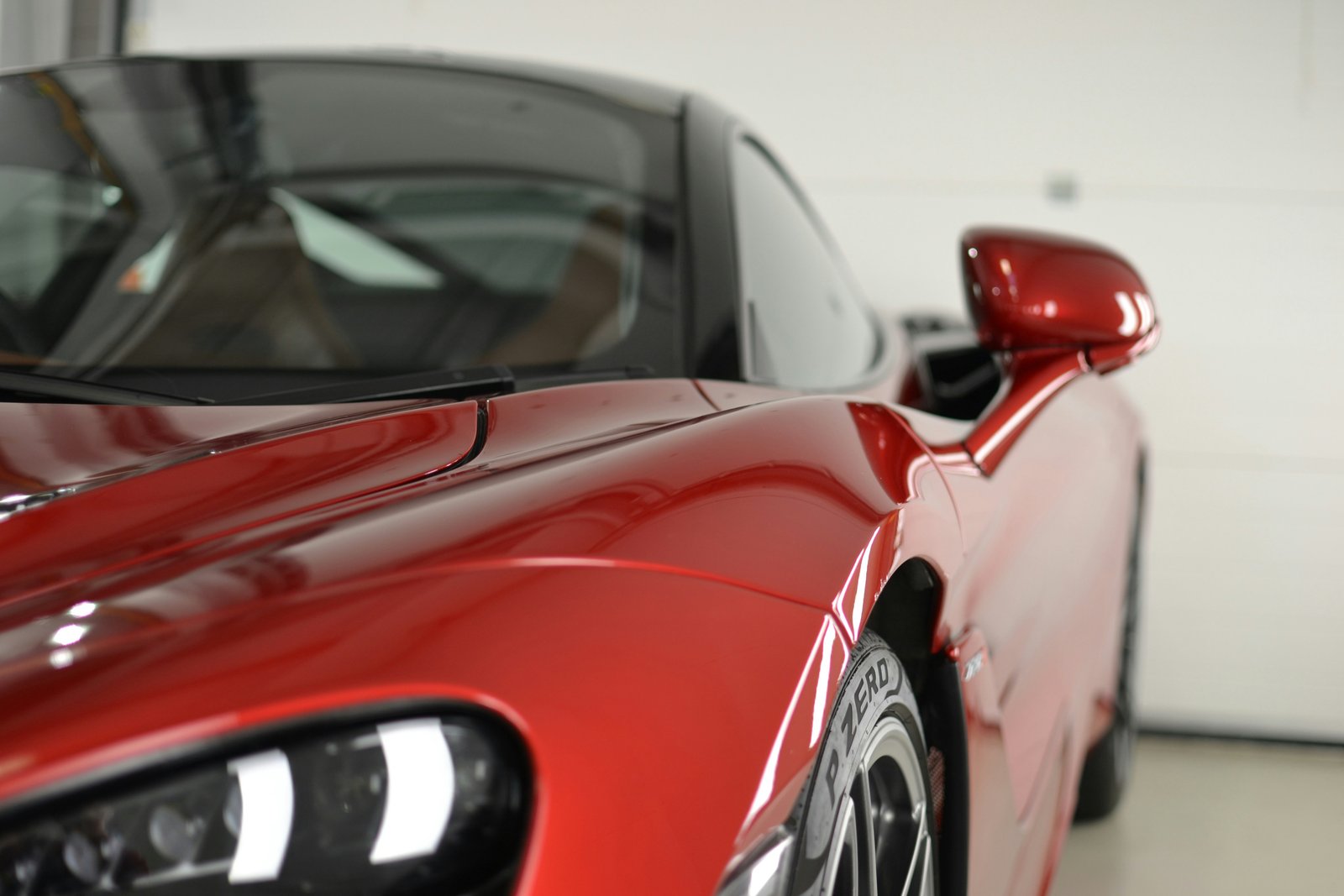Close-up of a red sports car with flawless glossy paintwork showing deep reflections after professional detailing