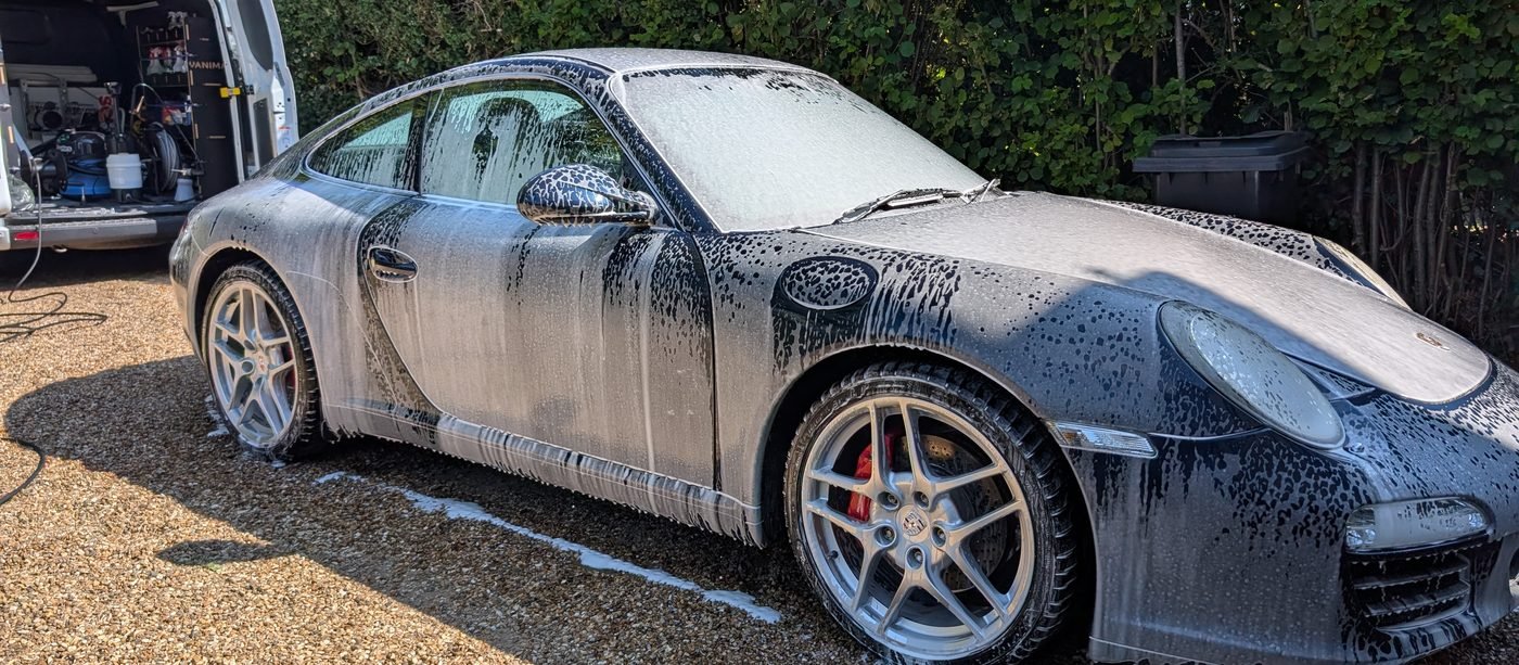 Porsche 911 covered in snow foam during a professional mobile valet on a driveway in Gerrards Cross