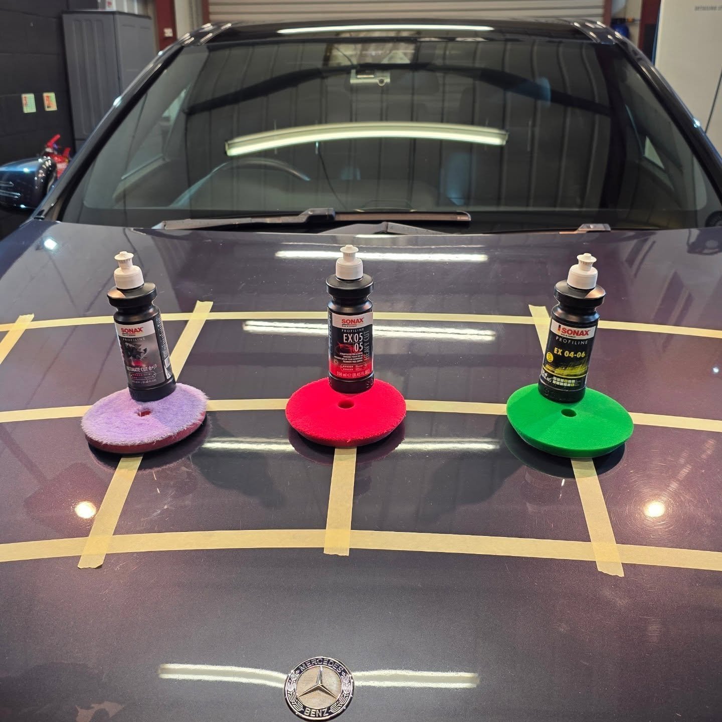 Three Sonax Profiline polishing compounds with matching polishing pads on a taped Mercedes bonnet ready for paint correction