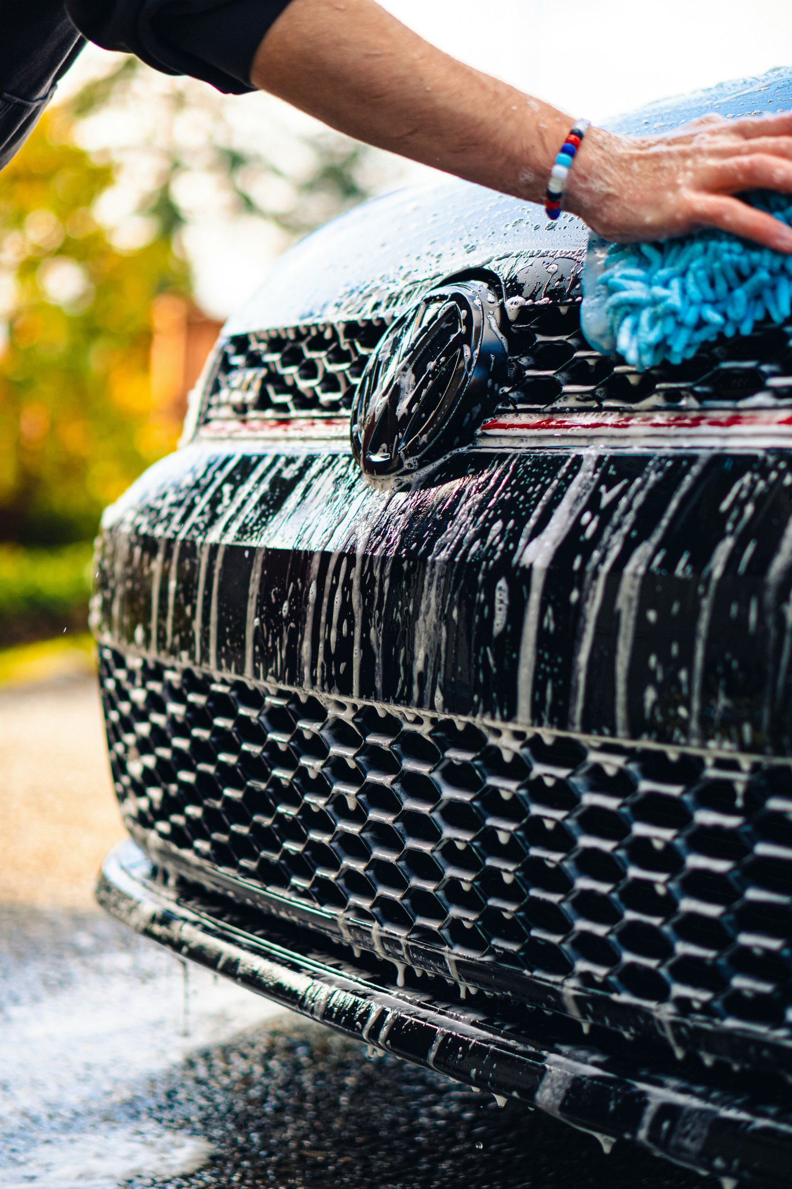 Professional hand washing a car using a microfibre mitt and safe wash method