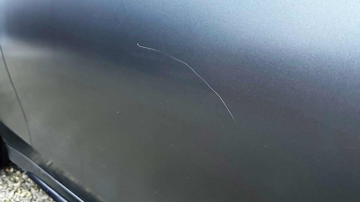 Fine scratch visible on car paint under inspection light