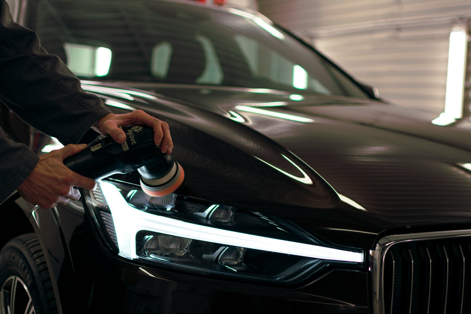 Professional machine polishing a car headlight as part of a paint correction service