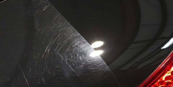 Swirl marks visible on dark paint under direct light